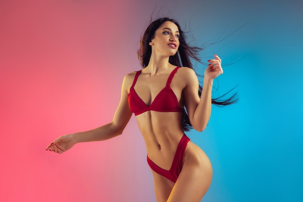 Retrato de moda de mujer joven y deportiva en elegante traje de baño rojo de lujo en pared degradada cuerpo perfecto listo para el verano