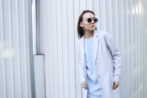 Retrato de moda de mujer joven elegante al aire libre en chaqueta, vestido, gafas. Look de moda de moda