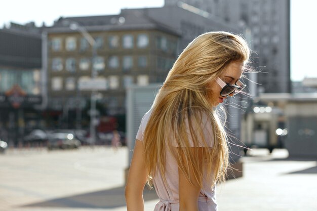 Retrato de moda de mujer joven hermosa con gafas de sol caminando por la calle. Espacio para texto