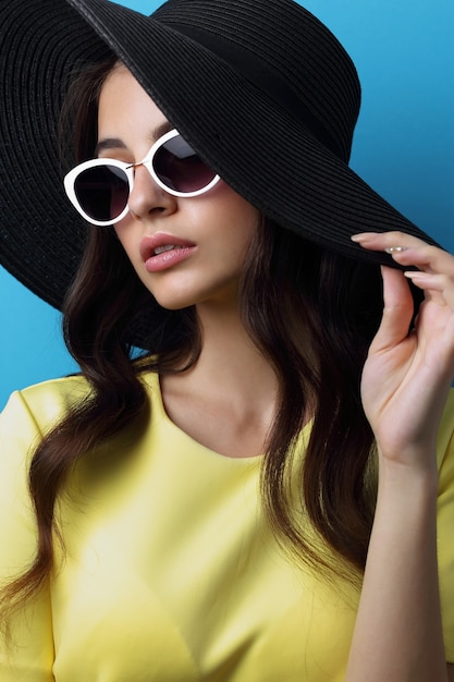 Retrato de moda de mujer joven con sombrero y gafas de sol.