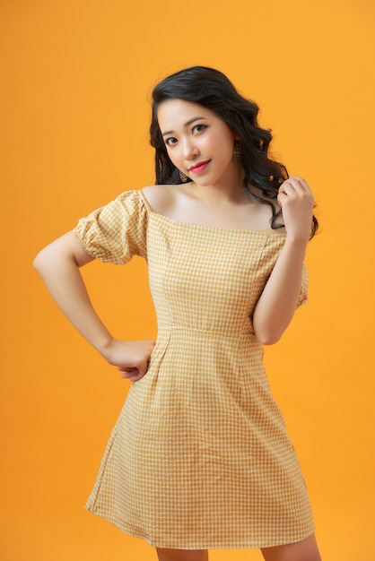 Retrato de moda de mujer joven sonriente atractiva en vestido amarillo sobre amarillo