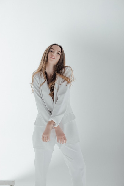 Retrato de moda de una mujer joven con traje blanco.