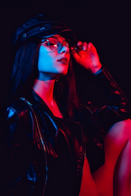 Retrato de moda de una mujer sexy con gafas en una chaqueta de cuero y gorra
