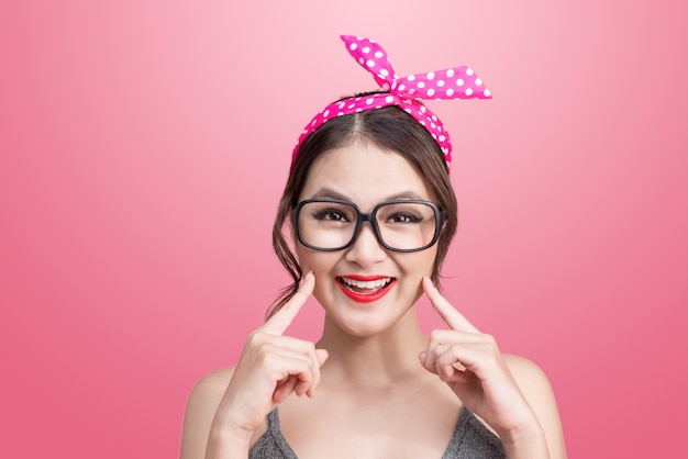 Retrato de moda de niña asiática con gafas de sol sobre fondo rosa.