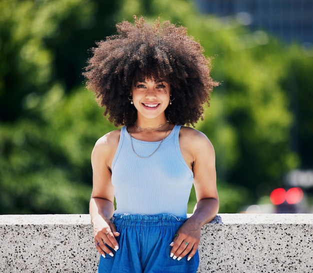 Retrato de moda y puente de la ciudad con una mujer negra al aire libre que parece relajada durante un día de verano Estilo callejero o urbano y una atractiva joven posando afuera con un peinado afro