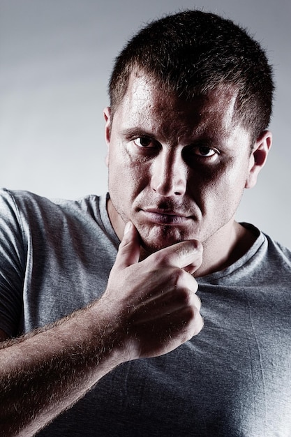 Retrato de un modelo de fitness atlético fuerte y saludable posando cerca de una pared gris oscuro