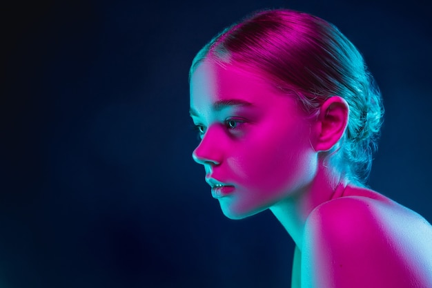 Retrato de modelo de moda femenina en luz de neón sobre fondo oscuro de estudio.