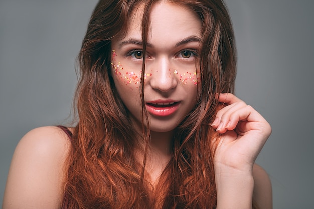 Foto retrato de modelo de moda. mujer joven pelirroja con destellos en las mejillas. expresión facial