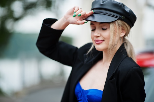 Retrato de modelo de mujer de moda sexy rubia hermosa en gorra y en todo negro con maquillaje brillante.