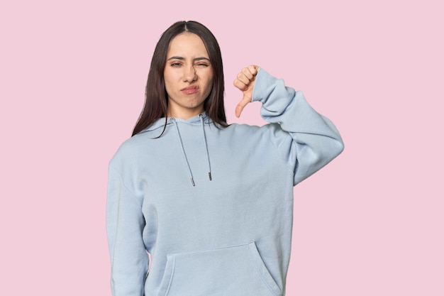 Retrato moderno de jovem mulher caucasiana em fundo de estúdio mostrando o conceito de decepção do polegar para baixo