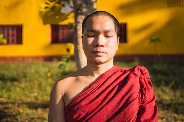 Retrato de un monje budista meditando con los ojos cerrados.