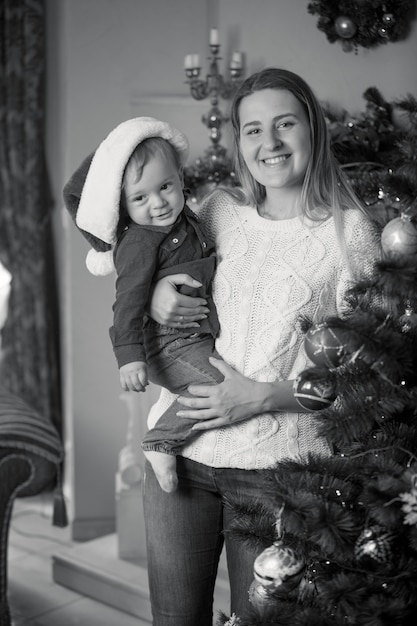 Retrato monocromo de feliz madre y niño decorar el árbol de Navidad