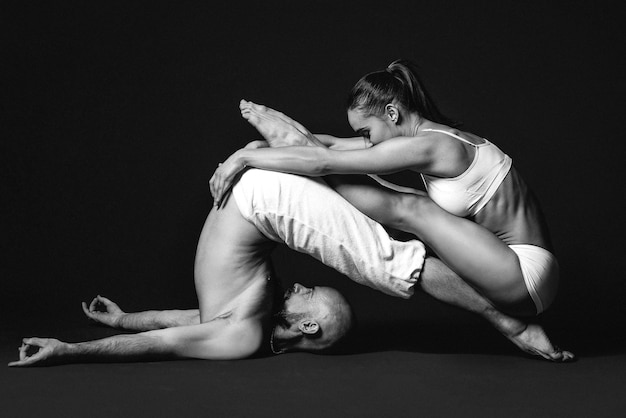 Retrato monocromo de hermosa pareja deportiva mujer y hombre en ropa blanca haciendo asanas de yoga