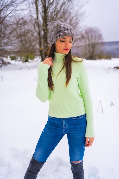 Retrato morena caucásica con traje verde y gorro de lana disfrutando de la nieve