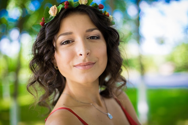 Retrato de una morena con flores en el pelo en un parque verde.