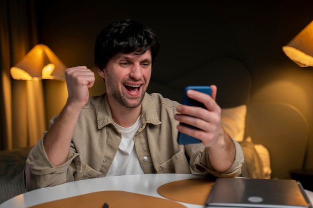 Retrato de una morena muy feliz y guapa leyendo un mensaje en su teléfono inteligente y celebrando el v