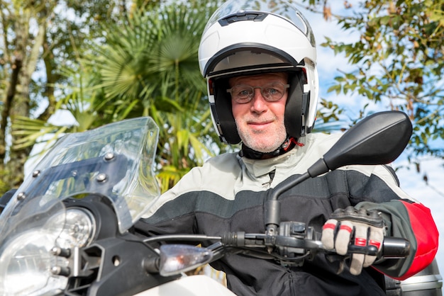 Retrato de un motociclista senior en su motocicleta