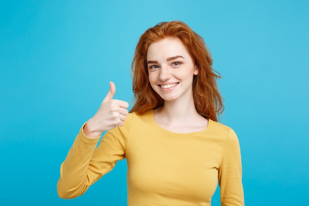 Retrato de la muchacha freckled con estilo joven que ríe con los golpes de la demostración para arriba en la cámara. Copie el espacio.