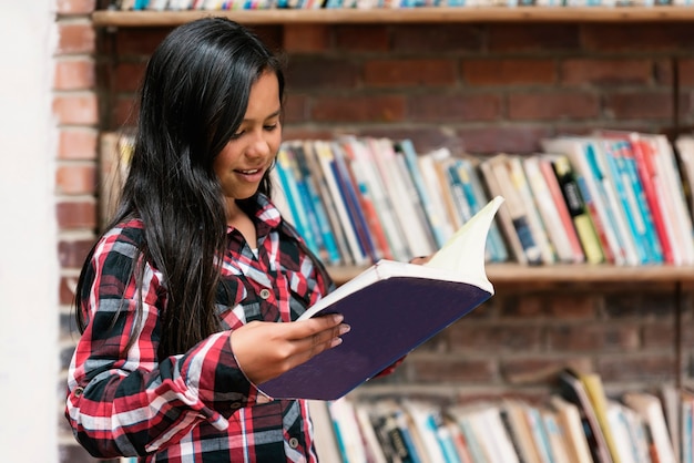 Retrato de muchacha hermosa estudiante en la biblioteca. Concepto infantil pobre