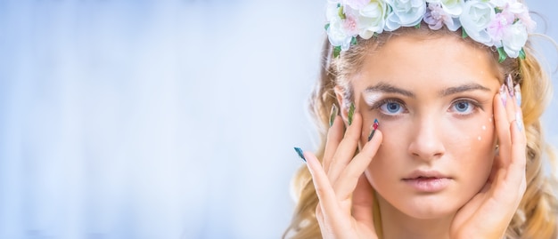 Retrato de muchacha hermosa con maquillaje creativo y uñas artísticas.