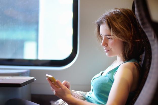Retrato de una muchacha hermosa que se comunica en el teléfono en un coche de tren