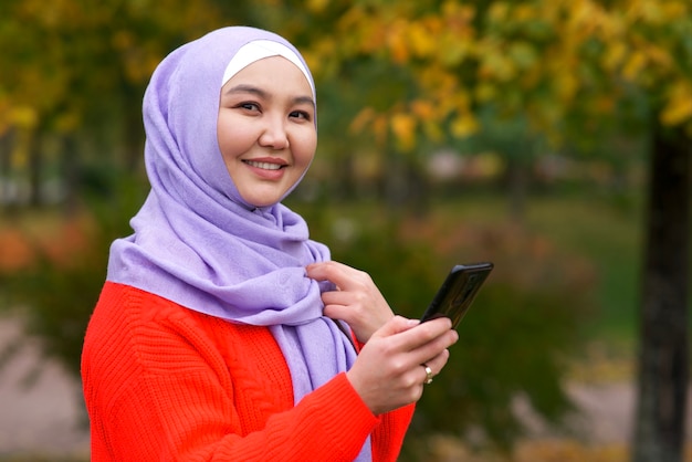 El retrato de la muchacha islámica de la mujer joven musulmana asiática hermosa feliz lleva la bufanda del hijab que sostiene