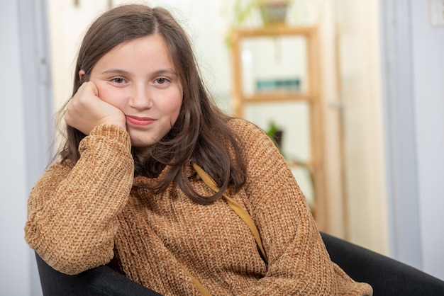 Retrato de la muchacha joven hermosa del adolescente que se sienta en la butaca