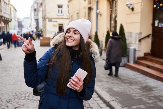 Retrato de una muchacha de moda joven que camina en la calle de la ciudad en invierno