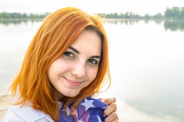 Retrato de la muchacha pelirroja sonriente feliz. Mujer joven positiva que mira in camera al aire libre.