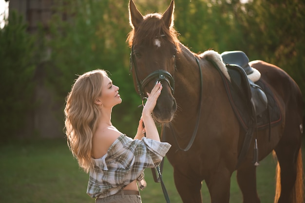 El retrato de la muchacha plaidó la camisa con el caballo negro en la granja del caballo.