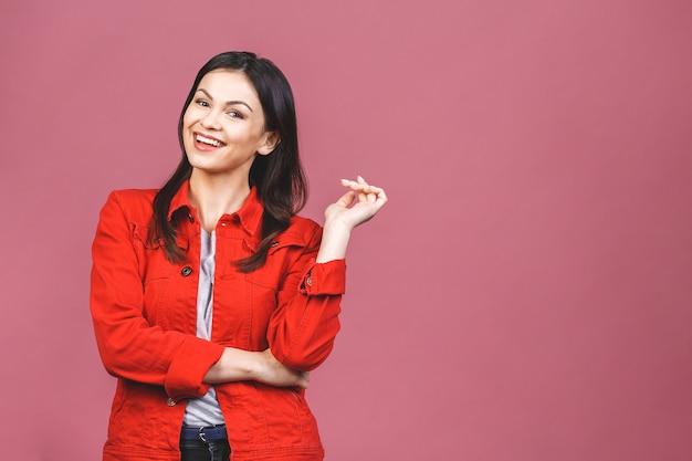 Retrato de la muchacha sonriente feliz del inconformista en casual aislado sobre la pared rosada.