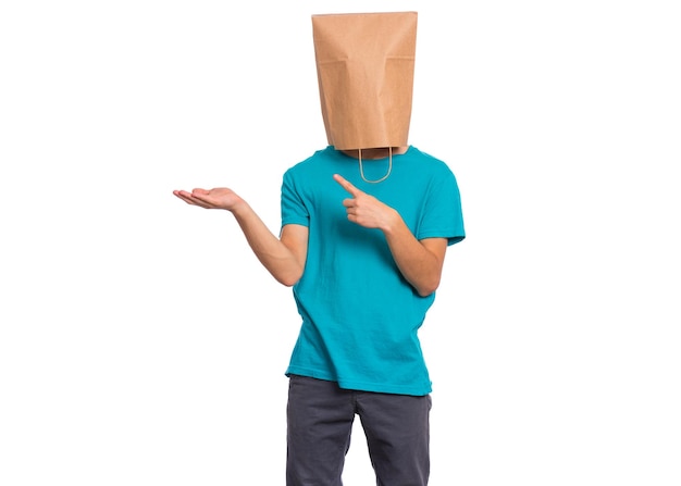 Retrato de muchacho adolescente con bolsa de papel sobre la cabeza apuntando con las manos lejos en copyspace sobre fondo blanco.