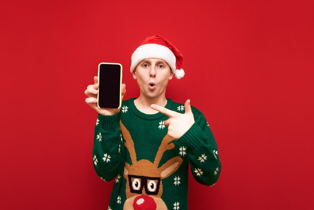 Retrato muchacho adolescente con suéter de Navidad sosteniendo teléfono