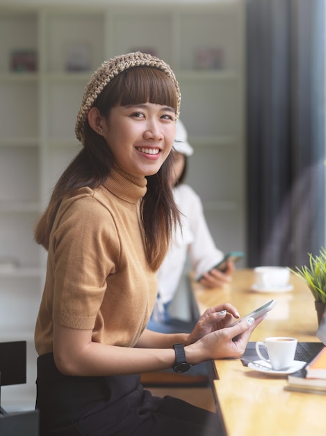 Retrato de mujer adolescente mirando a la cámara mientras realiza una asignación en el café