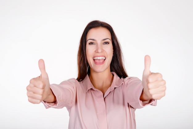 Retrato de una mujer adulta feliz que muestra los pulgares hacia arriba contra un fondo blanco