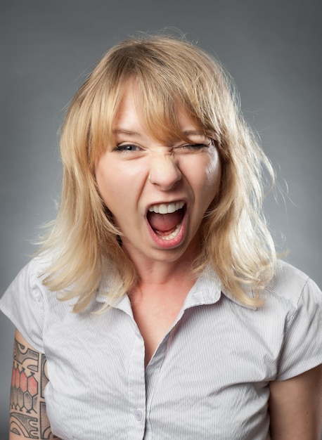 Foto retrato de una mujer adulta gritando en uniforme contra un fondo gris