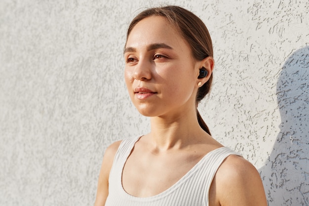 Retrato de mujer adulta joven con apariencia agradable con airpods mirando a otro lado con expresión soñadora