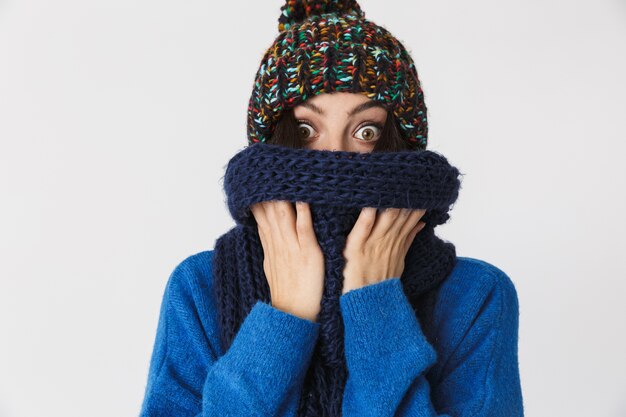 Retrato de mujer adulta vistiendo gorro de invierno y envuelto en cálida bufanda de pie, aislado en blanco