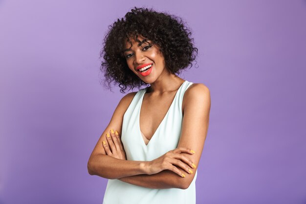 Retrato de una mujer africana alegre vistiendo un vestido que se encuentran aisladas sobre fondo violeta