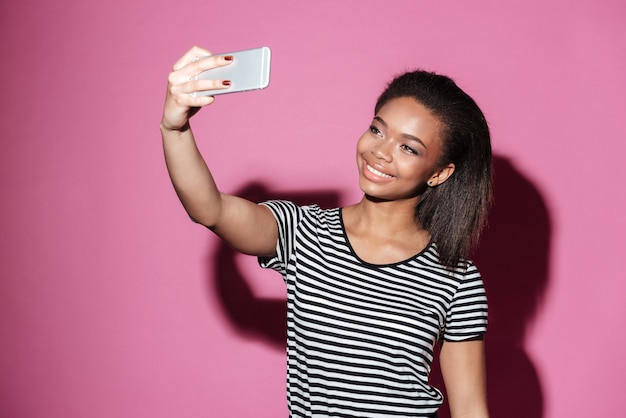 Retrato de una mujer africana joven feliz tomando selfie