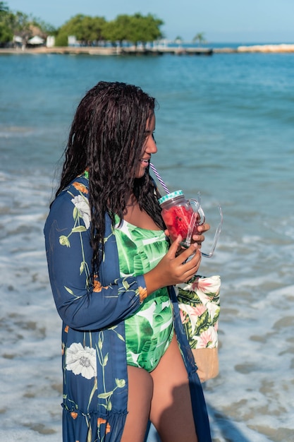 Retrato de mujer africana con jugo en la playa