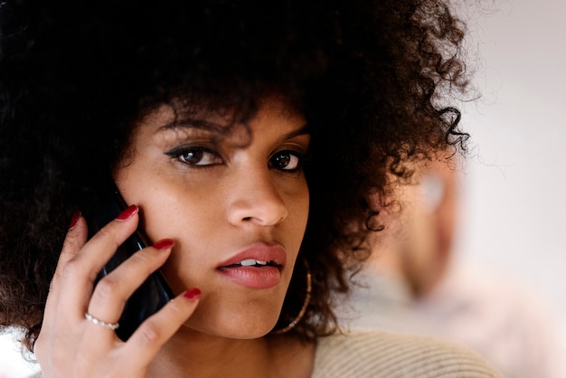 Retrato de mujer afro atractiva mediante teléfono móvil en la calle. Concepto de mujer de negocios