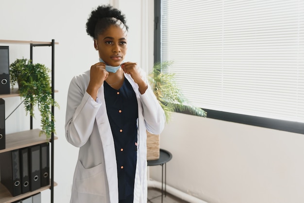 Retrato de mujer afroamericana feliz especialista en salud en máscara médica de cerca.