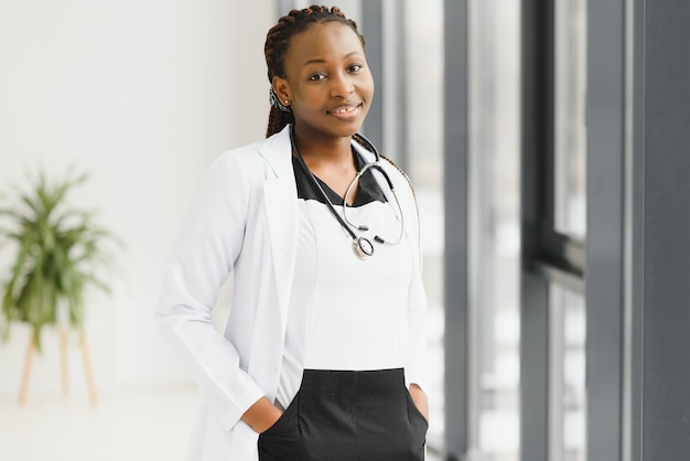 Retrato de mujer afroamericana médico de pie en su oficina en la clínica