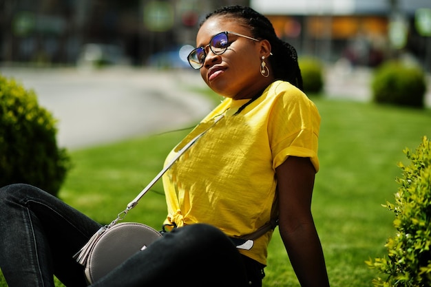 Retrato de mujer afroamericana negra en camiseta amarilla y gafas.