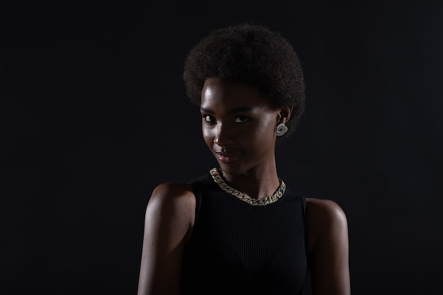 Retrato de mujer afroamericana con peinado afro sobre fondo negro de estudio de cerca