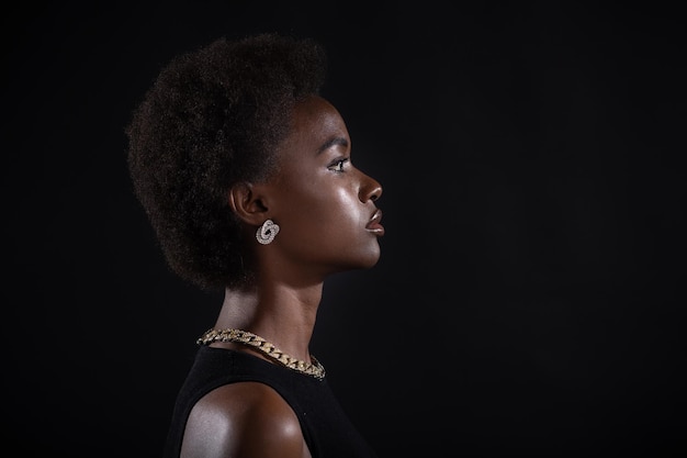 Retrato de mujer afroamericana con peinado afro sobre fondo negro de estudio de cerca