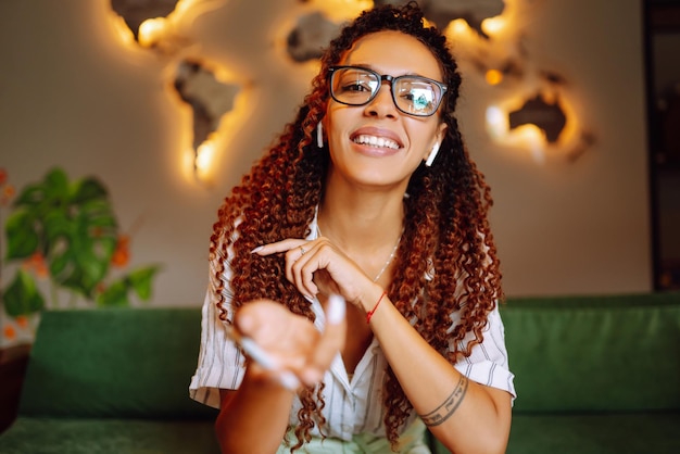 Retrato de una mujer afroamericana sentada en un café con una videollamada en una computadora portátil