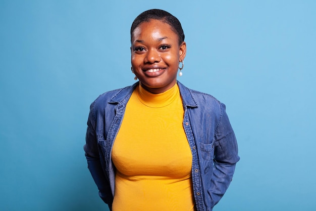 Retrato de mujer afroamericana sonriendo frente a la cámara. Adulto joven que se siente alegre y posando en el estudio, con una expresión facial alegre y positiva. Hermosa persona con piel oscura.