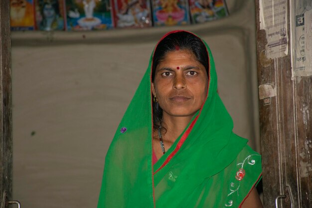 Foto retrato de una mujer de la aldea india que lleva un saristando contra una pared de barro